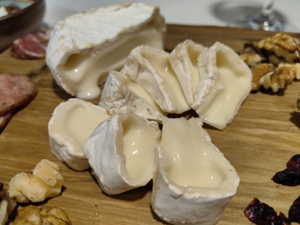 Camembert de Oveja Vasca cortado por la mitad, mostrando su interior cremoso, fundente y de color marfil pálido, en el punto perfecto de maduración para untar.