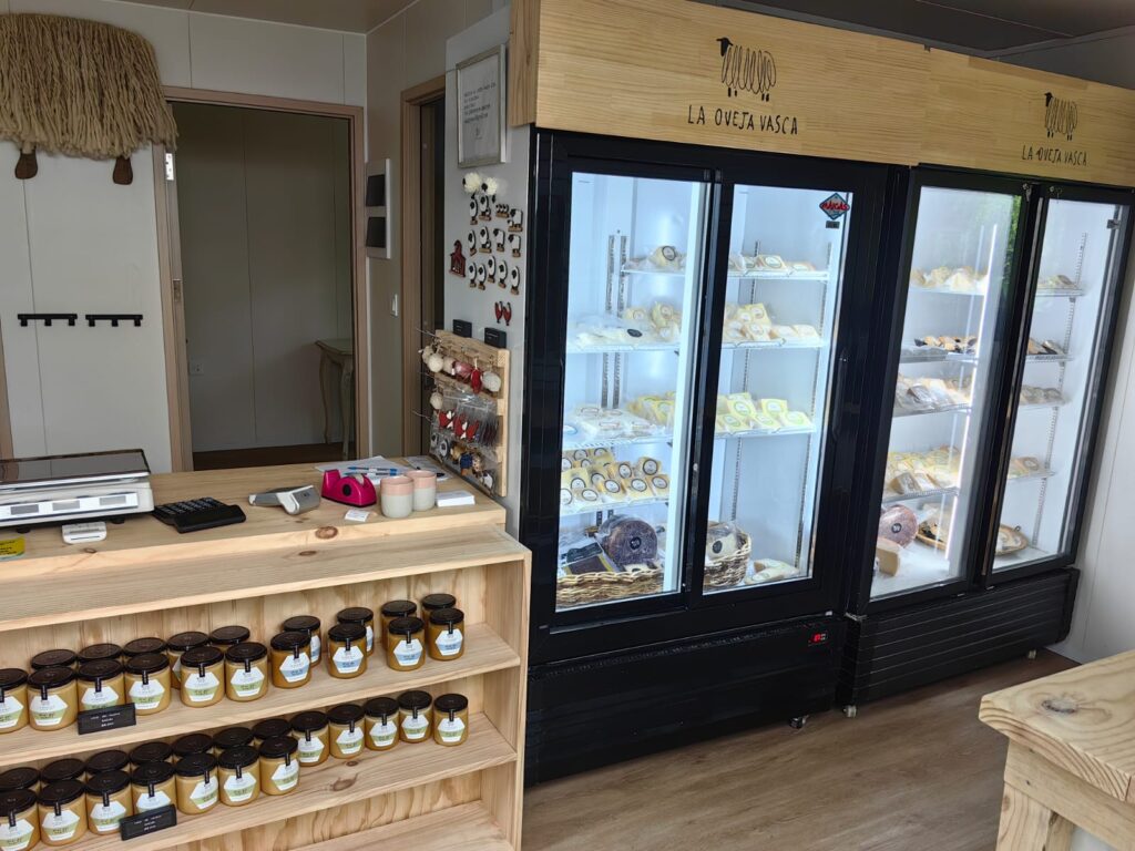 Punto de venta oficial de Oveja Vasca en una tienda gourmet, mostrando sus quesos de oveja artesanales exhibidos en refrigeración especializada junto a material de la marca.